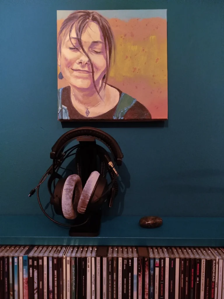 Portretje Genieten hangt aan de muur boven koptelefoon en cd's.